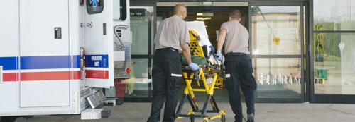 Paramedics taking patient on stretcher from ambulance to hospital 